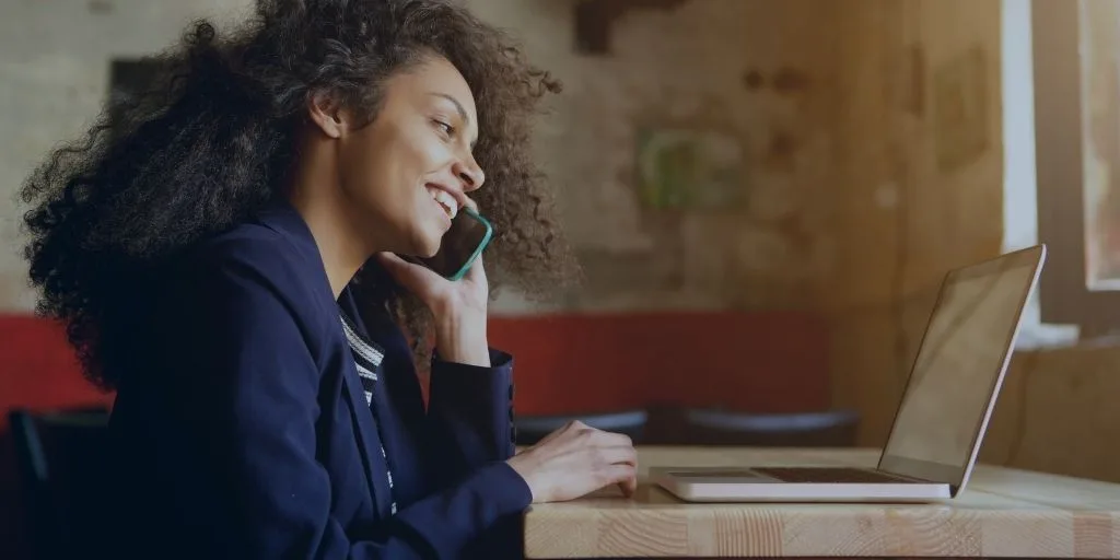 A woman talking on a cell phone in front of her computer